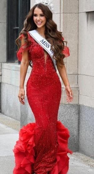 Aslıhan Moralı Miss Universe Canada kuşağı ve kırmızı elbisesiyle yürürken