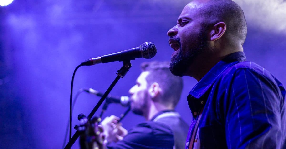 Bir konser sahnesinde mikrofonla performans sergileyen sanatçı