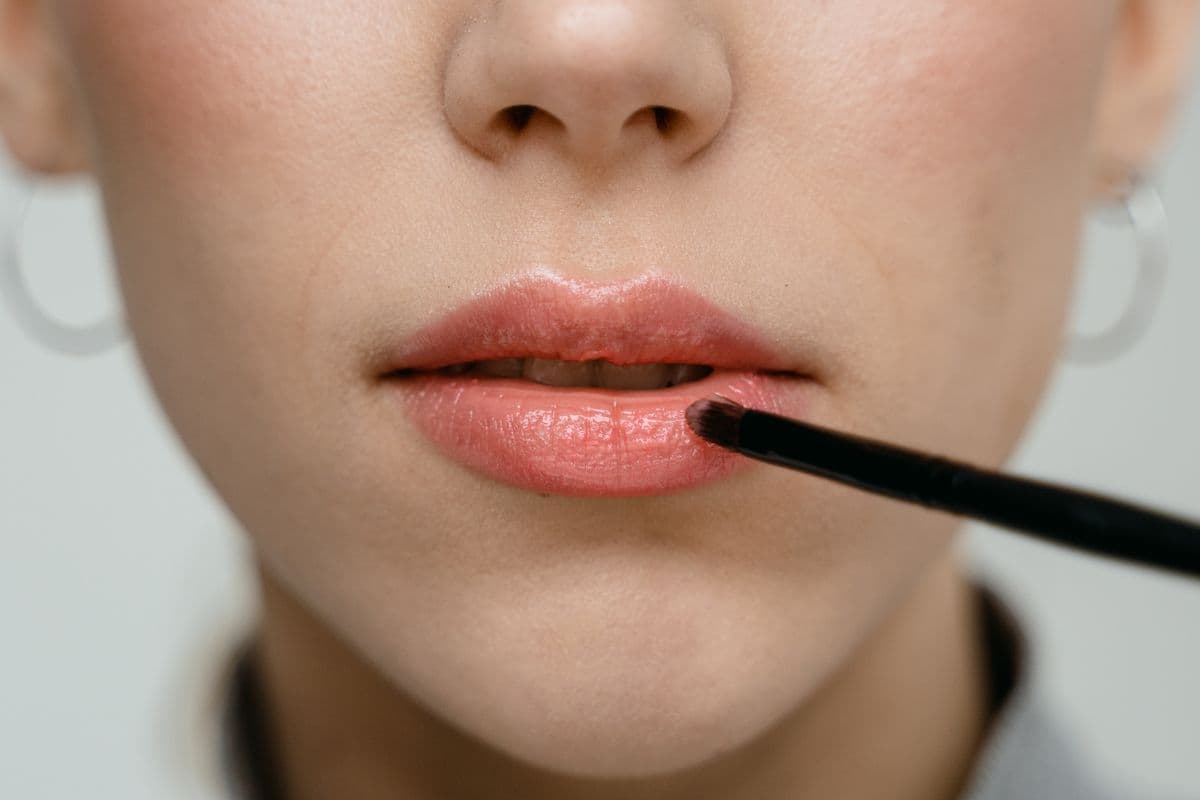 Cam bir kapta duran pembe tonlu kozmetik serum ve uygulama aparatı