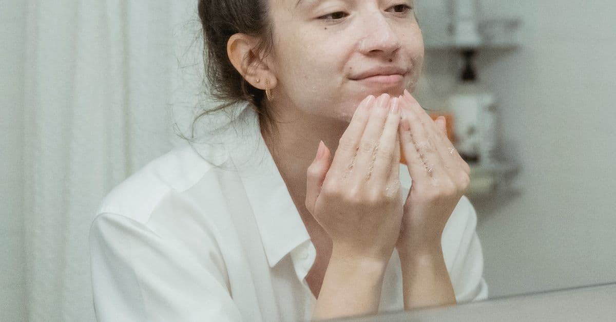 Gece cilt bakım rutini uygulayan kadın banyo aynası önünde