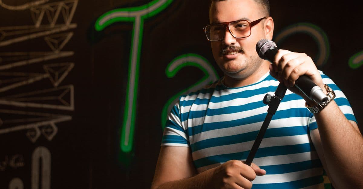 Mikrofon önünde sahne alan bir komedyeni temsil eden stok görsel