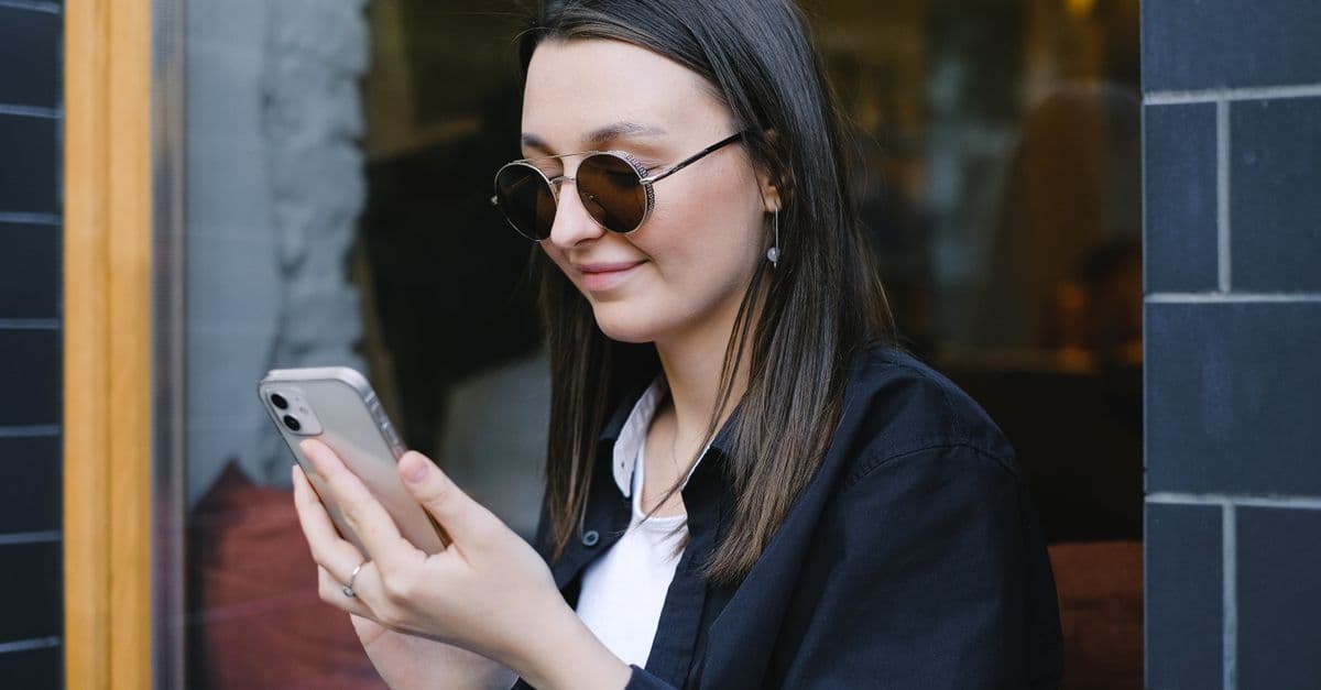 Telefon ekranında sosyal medya paylaşımına bakan bir kadın